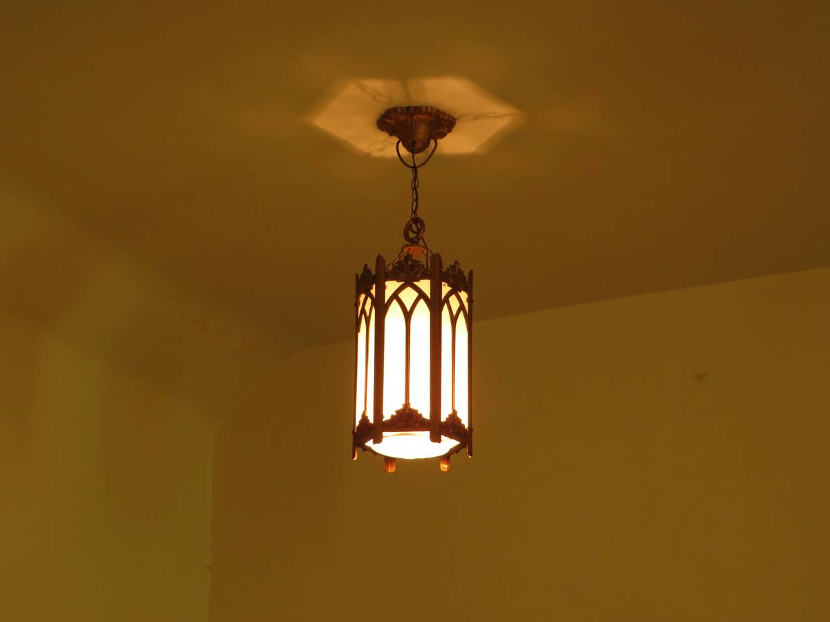 Mission lighting fixtures wall sconce installed beside oak doorway with warm filament bulb