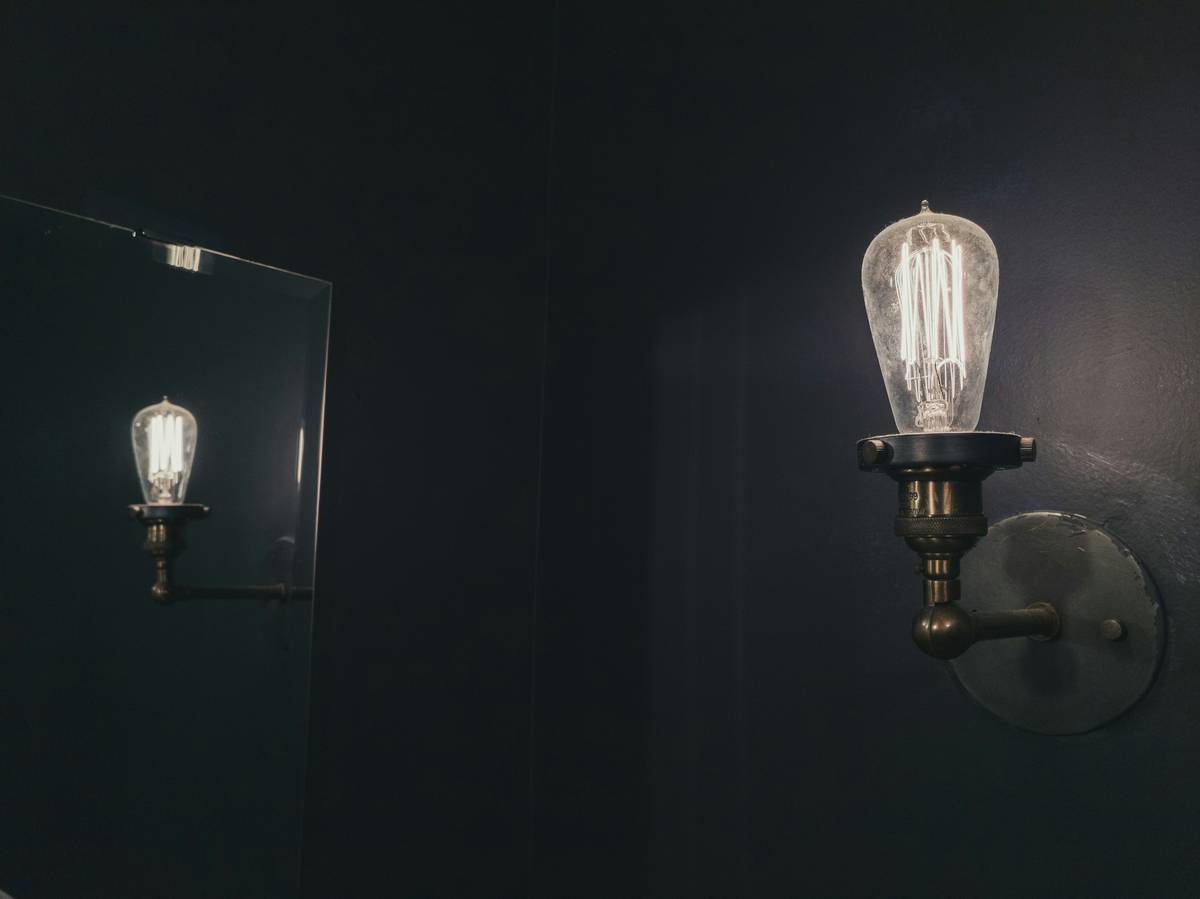 Unlacquered brass wall sconces lighting fixtures mounted beside a staircase with soft upward glow