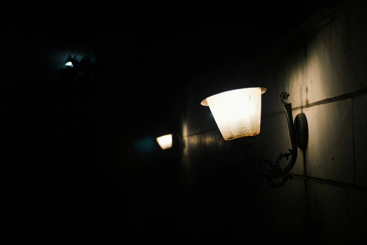 Close-up of stylish black wall sconce lighting fixtures beside a bathroom mirror with balanced illumination